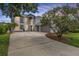 Stately two-story home with a three-car garage, lush landscaping, and an expansive driveway under a colorful sky at 4915 Augusta Ave, Oldsmar, FL 34677
