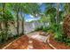 Secluded backyard area featuring mature trees, white fence, mulch, and a wooden seating area at 546 26Th N Ave, St Petersburg, FL 33704
