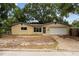 A single-story home boasting a beige exterior, attached garage, and front yard featuring mature trees for shade at 701 59Th Ne Ave, St Petersburg, FL 33703