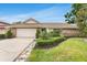 Beautiful single-story home featuring stone accents, a tile roof, manicured landscaping, and an attached two-car garage at 7032 Pelican Island Dr, Tampa, FL 33634