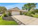 Lovely home featuring a 2-car garage, concrete driveway, stone details, tile roof, and a lush, green lawn at 7032 Pelican Island Dr, Tampa, FL 33634