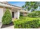 Charming front entrance featuring a tiled porch, stone accents, manicured bushes, and a well-maintained green lawn at 7032 Pelican Island Dr, Tampa, FL 33634