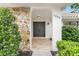 Close up of front entrance with tiled entry, stone accents, a stylish door, and curated landscaping at 7032 Pelican Island Dr, Tampa, FL 33634