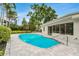 A sparkling pool surrounded by an interlocking brick patio, lush landscaping and the home's exterior at 7032 Pelican Island Dr, Tampa, FL 33634