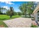 Beautifully designed brick paver patio overlooking a lush, expansive backyard with mature trees at 7103 Bridgeview Dr, Wesley Chapel, FL 33545
