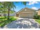Inviting single-story home showcasing a two-car garage, lush green lawn, and mature trees in a residential neighborhood at 7103 Bridgeview Dr, Wesley Chapel, FL 33545