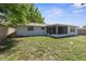 Backyard view of the house with a screened in patio and grassy lawn at 7215 San Moritz Dr, Port Richey, FL 34668