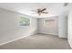 Neutral bedroom featuring wall-to-wall carpet, a ceiling fan and two windows at 7215 San Moritz Dr, Port Richey, FL 34668
