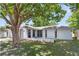 Well-maintained single-story home featuring an arched entryway, large tree, and tidy landscaping at 7215 San Moritz Dr, Port Richey, FL 34668