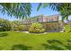 A lush green lawn leads up to a two-story house with a deck overlooking a meticulously landscaped backyard, perfect for outdoor enjoyment at 80 Sycamore Ct, Palm Harbor, FL 34683