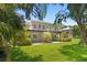 Spacious backyard with mature trees and a two-story home featuring a large balcony at 80 Sycamore Ct, Palm Harbor, FL 34683