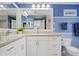 A blue bathroom is equipped with double sinks, white cabinets, and a wide mirror with great lighting at 80 Sycamore Ct, Palm Harbor, FL 34683