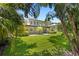 Charming two-story home featuring a spacious backyard with a well-manicured lawn and tropical landscaping at 80 Sycamore Ct, Palm Harbor, FL 34683