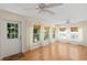 Sunlit living room with hardwood floors, multiple windows, and white curtains and blinds at 80 Sycamore Ct, Palm Harbor, FL 34683