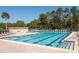Community pool with marked lanes, surrounded by lounging chairs, and a building at 80 Sycamore Ct, Palm Harbor, FL 34683
