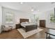 Spacious main bedroom with a wood-framed bed, hardwood floors, three windows, and neutral-toned decor at 807 W Kentucky Ave, Tampa, FL 33603
