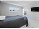 Bright bedroom featuring neutral carpet, balcony access, and a sleek wall-mounted TV at 10216 Regal Dr # 208, Largo, FL 33774