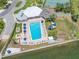 Aerial view of community outdoor pool with lounge chairs, playground, tennis court, and views of the waterfront at 10216 Regal Dr # 208, Largo, FL 33774