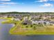 Aerial view of a neighborhood featuring spacious homes, green lawns, and a serene lake in the background at 11878 Thicket Wood Dr, Riverview, FL 33579