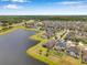 Wide aerial view of a residential neighborhood featuring a serene lake and lush green spaces at 11878 Thicket Wood Dr, Riverview, FL 33579
