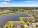 Expansive aerial view of a home with scenic lake, tree coverage, and a well-maintained lawn at 11878 Thicket Wood Dr, Riverview, FL 33579