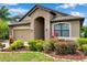 Charming home featuring a stone-arched entryway, complemented by lush greenery and a neatly maintained lawn at 11878 Thicket Wood Dr, Riverview, FL 33579