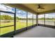 Relaxing screened-in porch with a ceiling fan, offering views of the backyard and a scenic lake at 11878 Thicket Wood Dr, Riverview, FL 33579