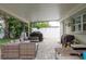 Covered outdoor patio area featuring wicker seating, grill, and view of landscaped yard at 11991 104Th Ave, Seminole, FL 33778