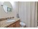 Neutral-toned bathroom featuring a granite countertop, framed mirror, and shower with neutral-striped curtain at 12009 Whistling Wind Dr, Riverview, FL 33569