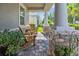 Relaxing front porch featuring stone pillars, brick flooring, comfortable wooden chairs, and lush potted plants at 12009 Whistling Wind Dr, Riverview, FL 33569