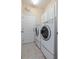 Well-lit laundry room with side-by-side washer and dryer, tile floor, and storage cabinets at 12009 Whistling Wind Dr, Riverview, FL 33569