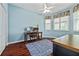 Bright office featuring a ceiling fan, wooden floors, blue walls, and a large window with a patterned valance at 12009 Whistling Wind Dr, Riverview, FL 33569