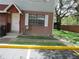 Close-up of a condo exterior with a red brick facade, a white trimmed door, and a parking space at 12780 N 57Th St, Tampa, FL 33617