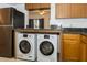 Kitchen featuring wood cabinets, dark countertops and stainless steel appliances including a modern washer and dryer at 12780 N 57Th St, Tampa, FL 33617