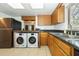 Kitchen featuring wood cabinets, dark countertops, stainless steel fridge and modern washer and dryer appliances at 12780 N 57Th St, Tampa, FL 33617