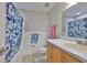 This bathroom features a tub with a blue shower curtain, white tile, wood cabinet, and a granite countertop at 13125 Wilcox Rd # 16202, Largo, FL 33774