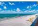 Beach view with beachgoers, umbrellas, and ocean waves under a partly cloudy sky at 14146 Gulf Blvd # 4B, Madeira Beach, FL 33708