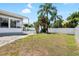 A spacious backyard featuring a pool, tropical plants, white fencing, and Florida room access at 1530 Picardy Cir, Clearwater, FL 33755