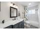 Bathroom featuring a gray vanity, marble countertop, and shower with tile surround at 1530 Picardy Cir, Clearwater, FL 33755