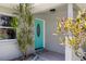 Inviting entryway featuring a bright, teal front door with decorative glass and colorful foliage at 1530 Picardy Cir, Clearwater, FL 33755