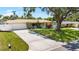 Charming single-story home with a well-manicured lawn, mature trees, and a spacious driveway leading to the garage at 1530 Picardy Cir, Clearwater, FL 33755