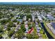 Residential area aerial view featuring a home, marked with a red arrow, near a canal, pool, and townhouses at 1573 Cumberland Ln, Clearwater, FL 33755