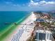Stunning aerial view of a vibrant beach with a pier and turquoise waters, highlighting the coastal lifestyle at 1573 Cumberland Ln, Clearwater, FL 33755