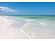 Serene beach scene with gentle waves lapping onto the sandy shore under a clear sky, showcasing a relaxing coastal lifestyle at 1573 Cumberland Ln, Clearwater, FL 33755