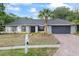 Charming one story home featuring grey brick, a brick driveway, landscaping, and a mailbox at 16014 Amberly Dr, Tampa, FL 33647