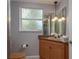 Bathroom featuring a wood vanity, decorative window, toilet, mirror, pendant lights, and tile floor at 2279 Ranchette Ln, Dunedin, FL 34698