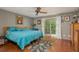 Bedroom featuring a blue bed, hardwood floors, ceiling fan, and sliding glass doors to the balcony at 2279 Ranchette Ln, Dunedin, FL 34698