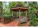 Wooden gazebo with seating offers a serene spot in the wooded backyard at 2279 Ranchette Ln, Dunedin, FL 34698