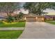 Charming single-Gathering home with a spacious two-car garage, complimented by lush landscaping at dusk at 2713 Brianholly Dr, Valrico, FL 33596