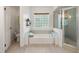 Well-lit bathroom with a separate shower, tub, glass block window and white fixtures, perfect for relaxation at 2713 Brianholly Dr, Valrico, FL 33596